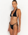 side view elegant woman wearing luxury swimsuit from sommer swim - ryan nero is a black bikini with halter style bikini top